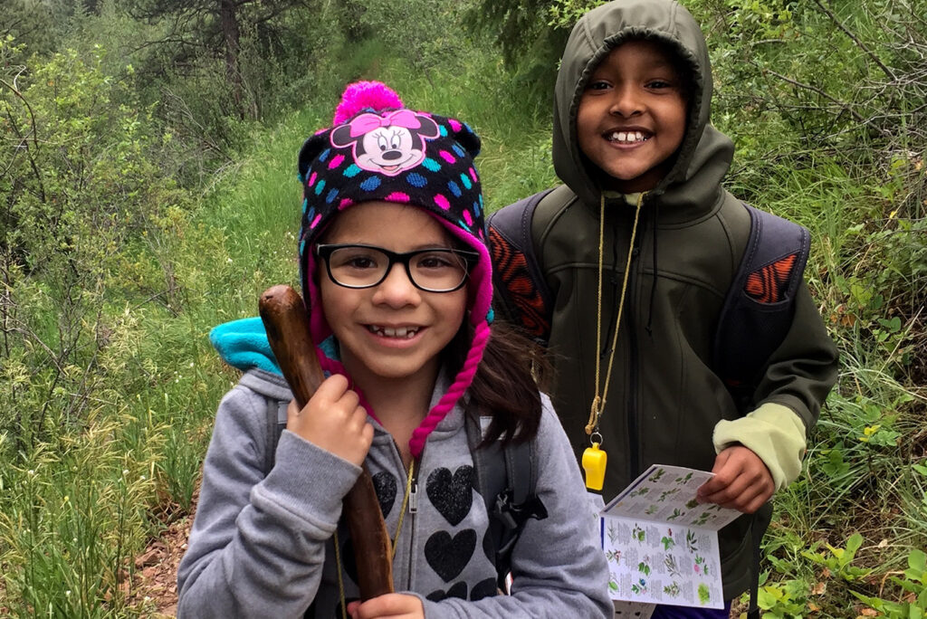 A photo of two kids smiling while out on a nature walk from one of The Cairn Project's grantees