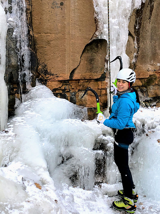 Liz Pham holds two ice axes at the bottom of an ice climb