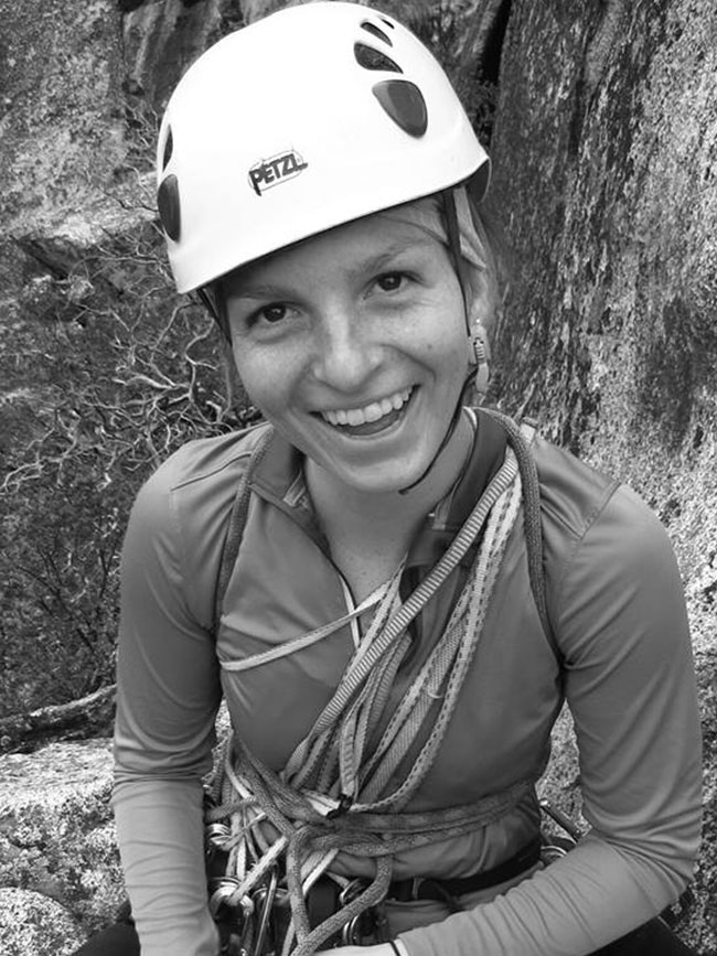 Cairn Project Ambassador Laura Wildenborg smiles wearing a climbing helmet, harness, and slings over her shoulder