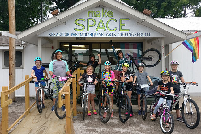 A group of girls on bikes in front of the makeSPACE building