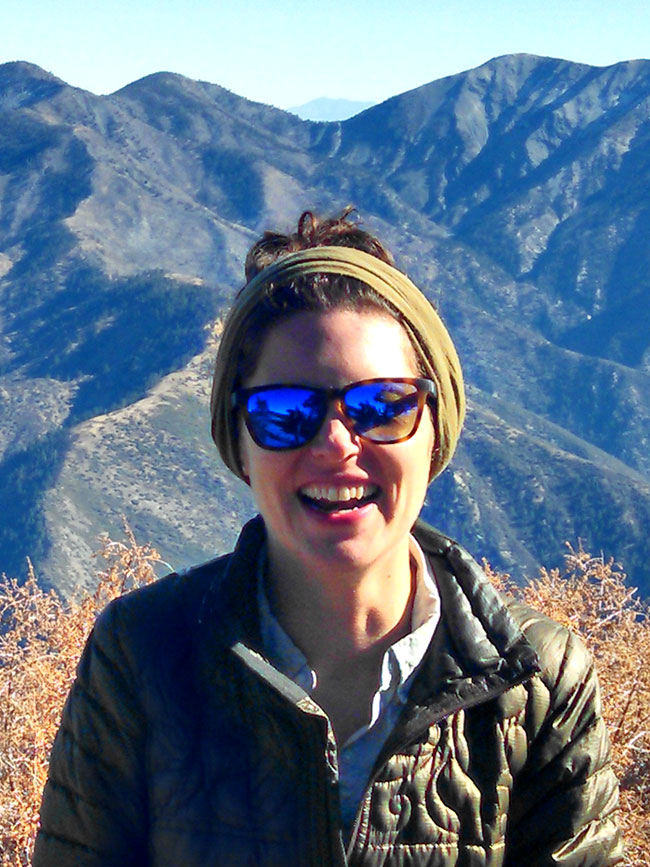 Cairn Project Ambassador Brooke Osborne smiles big wearing sunglasses with mountains behind her