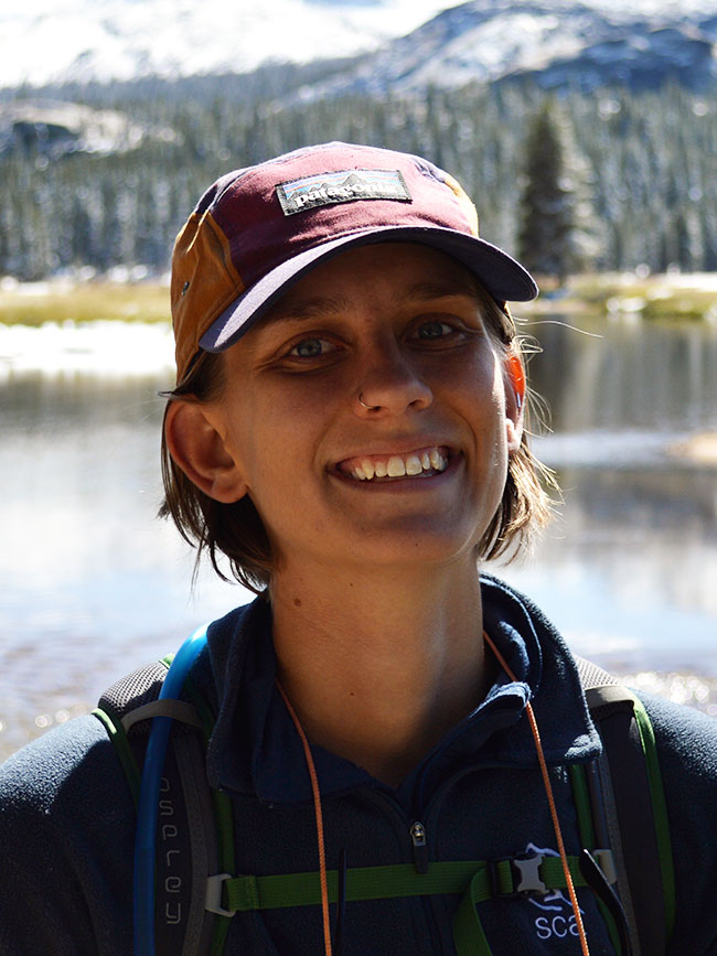 Cairn Project Ambassador Julia Oleksiak smiles with mountains and a lake behind her