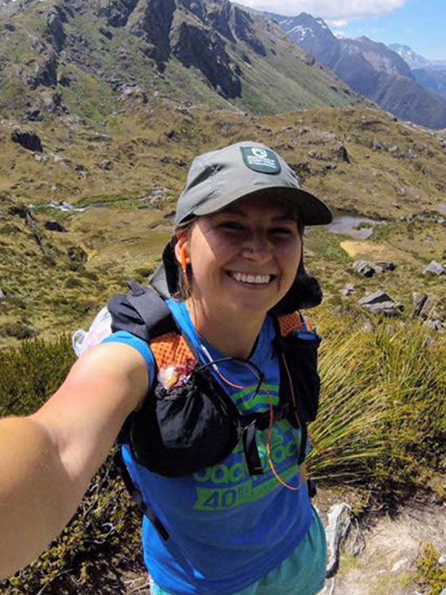 Cairn Project Ambassador Nicki Klein takes a selfie in mountains wearing a running pack