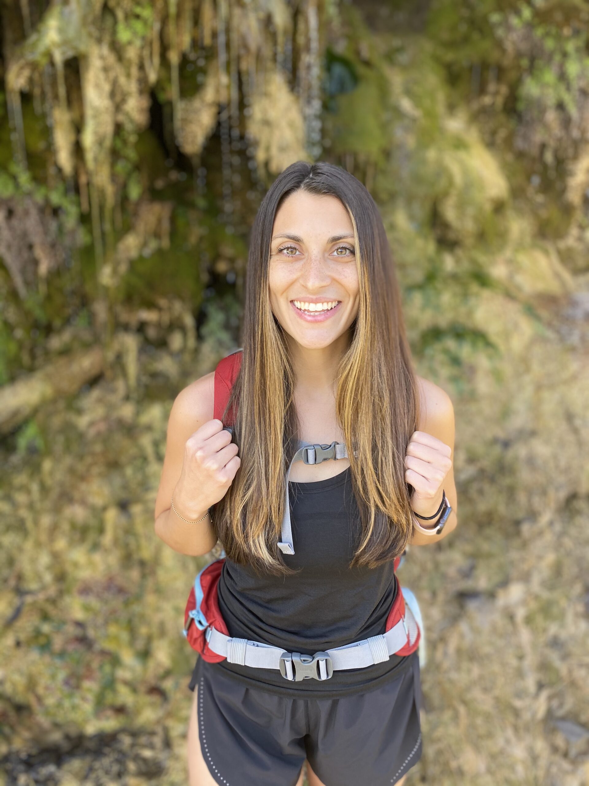 Cairn Project Ambassador Katie Koumarianos smiles wearing a backpack and hiking clothes