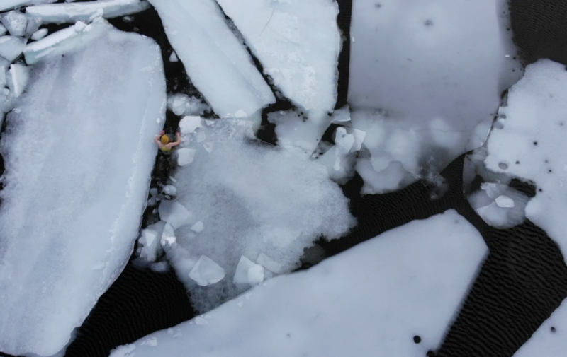 An aerial view of Annie Le in a dark lake full of ice chunks