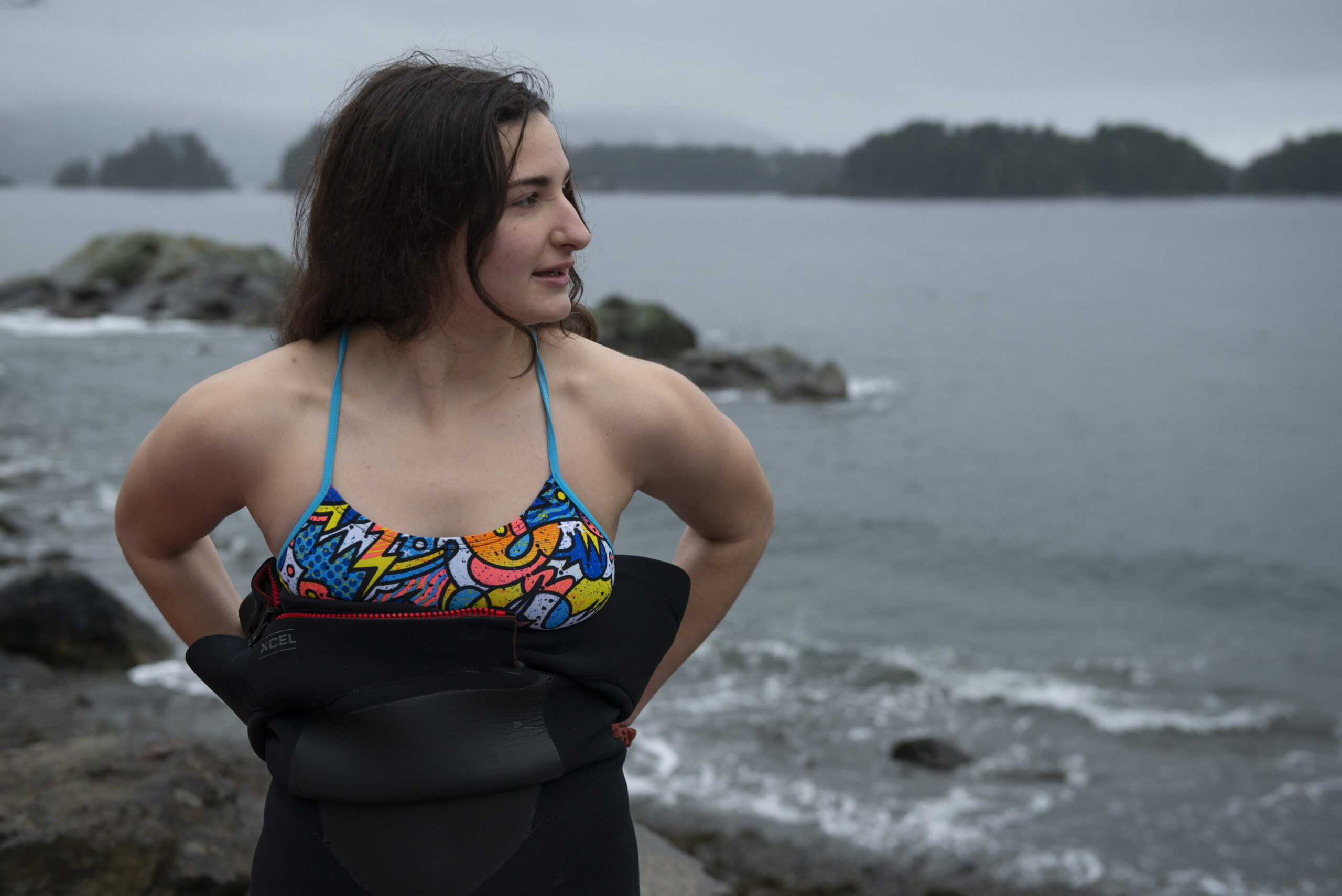Cairn Project Ambassador AK puts on a wetsuit with a gloomy water scene behind her