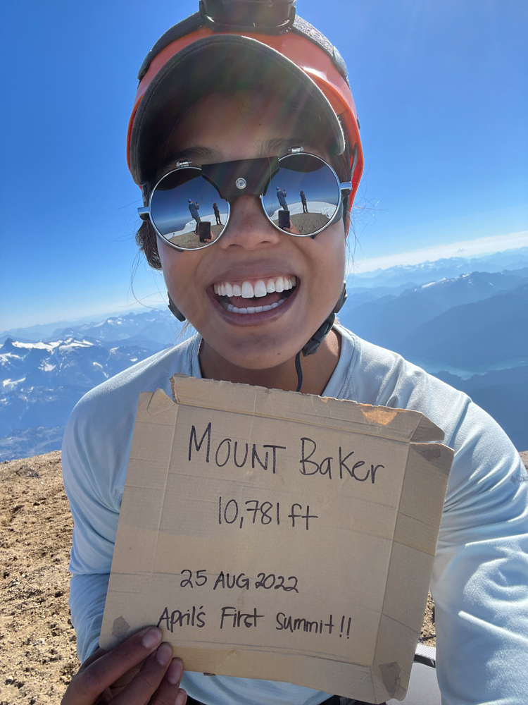 april smiles to the camera holding a sign that says mount baker